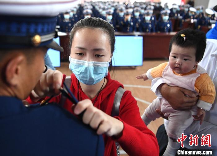 新消防員楊振的妻子彭莉與女兒現(xiàn)場見證丈夫加入“火焰藍(lán)”的神圣時(shí)刻?！⒅铱?攝