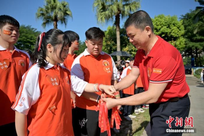 資料圖：廣西華僑實(shí)驗(yàn)高中的教師為高三學(xué)子系上紅絲帶，盼望學(xué)子高考必勝。 俞靖 攝